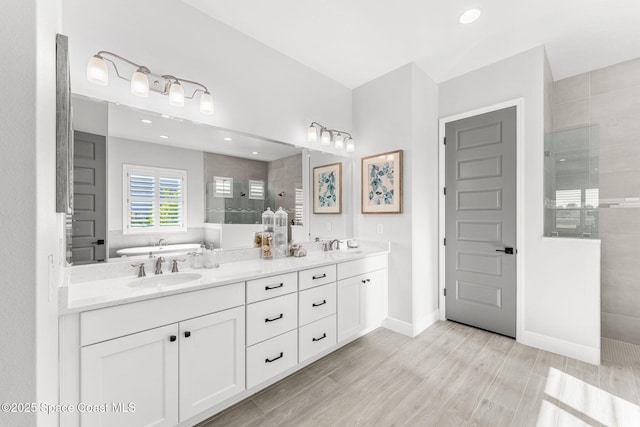 bathroom with a tile shower, vanity, and wood-type flooring