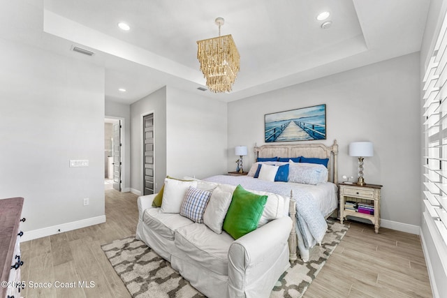 bedroom featuring a tray ceiling and a chandelier