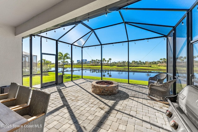 view of patio with a water view, area for grilling, a fire pit, and glass enclosure