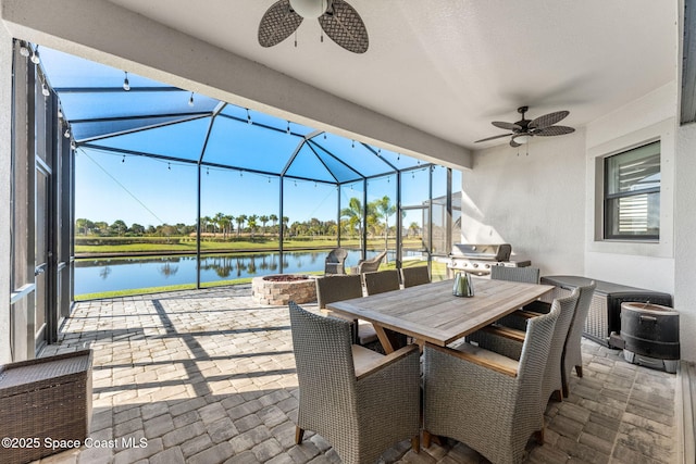 view of patio / terrace with a fire pit, grilling area, ceiling fan, glass enclosure, and a water view