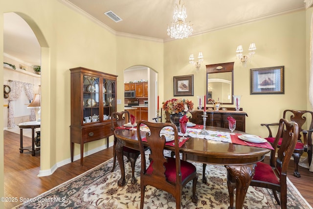 dining room featuring a notable chandelier, crown molding, and hardwood / wood-style flooring