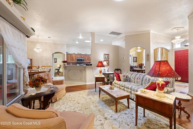 living room with a textured ceiling, plenty of natural light, crown molding, and light hardwood / wood-style flooring