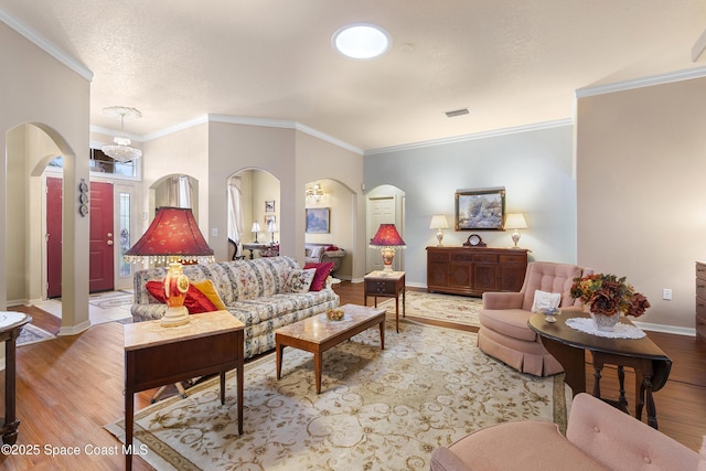 living room with a textured ceiling, ornamental molding, and light hardwood / wood-style floors