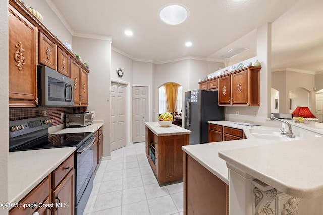 kitchen featuring kitchen peninsula, stainless steel appliances, a kitchen island, crown molding, and sink