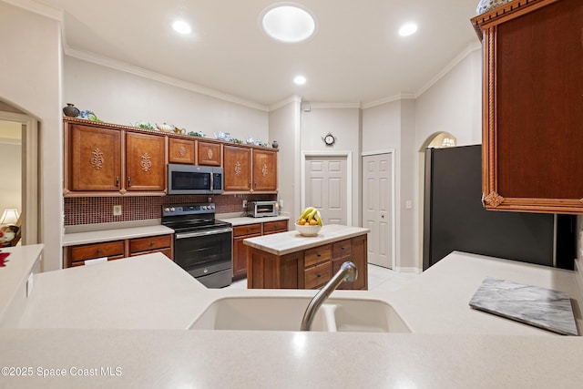 kitchen with appliances with stainless steel finishes, a kitchen island, sink, backsplash, and ornamental molding