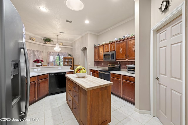 kitchen with pendant lighting, appliances with stainless steel finishes, a kitchen island, tasteful backsplash, and butcher block countertops