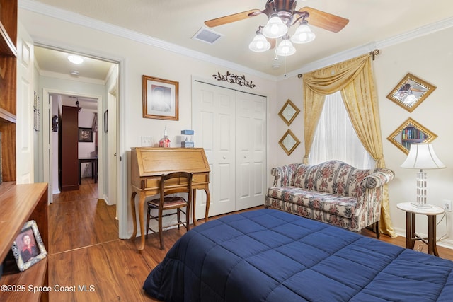 bedroom featuring a closet, dark hardwood / wood-style flooring, crown molding, and ceiling fan