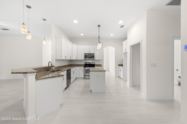 kitchen with white cabinetry, kitchen peninsula, stainless steel appliances, a center island, and sink