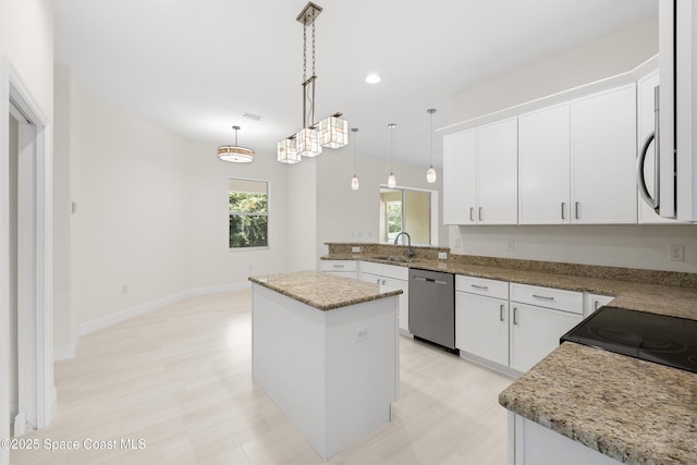 kitchen featuring stainless steel dishwasher, white cabinets, pendant lighting, and a center island