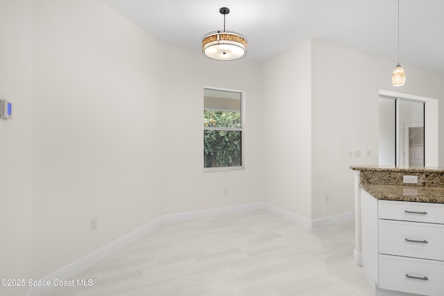 interior space with decorative light fixtures, white cabinets, and dark stone countertops