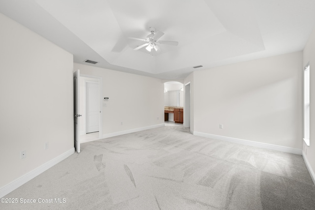 unfurnished living room with light carpet, ceiling fan, and a tray ceiling