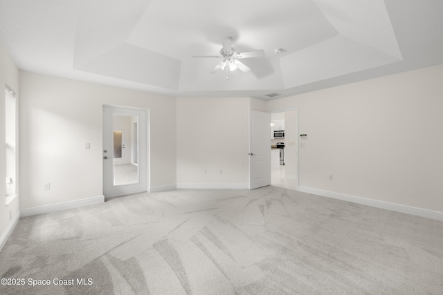 carpeted spare room with ceiling fan and a tray ceiling