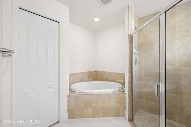 bathroom with a textured ceiling, tile patterned flooring, and shower with separate bathtub