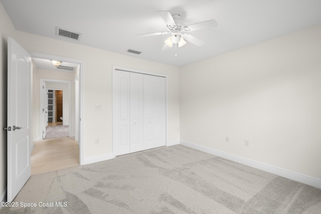 unfurnished bedroom featuring ceiling fan, light colored carpet, and a closet