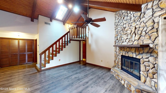 unfurnished living room featuring ceiling fan, a fireplace, hardwood / wood-style floors, high vaulted ceiling, and beamed ceiling