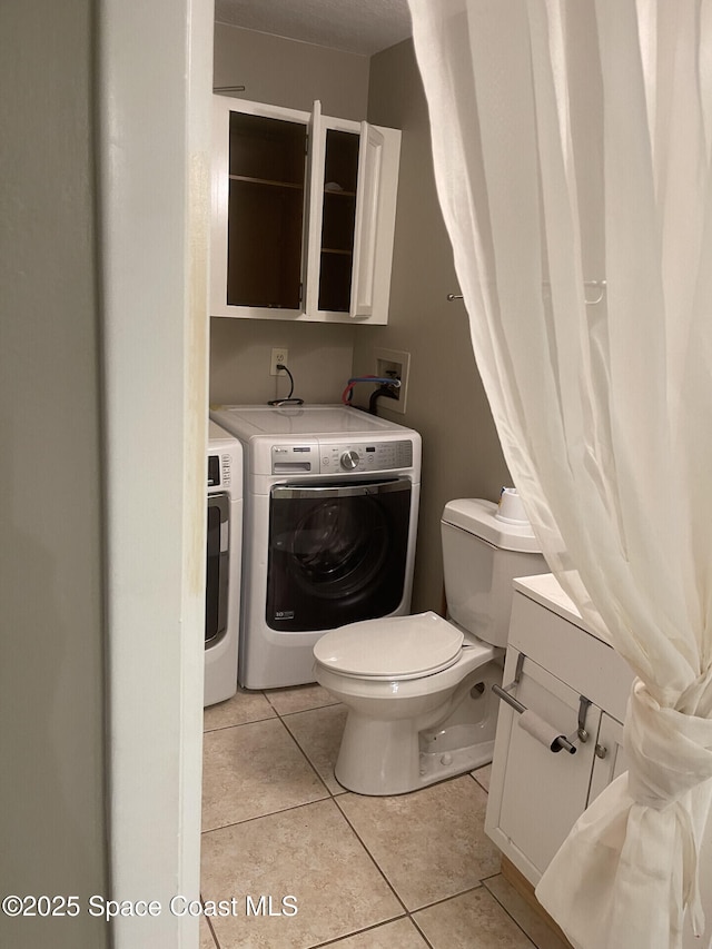 bathroom with toilet, tile patterned floors, and separate washer and dryer