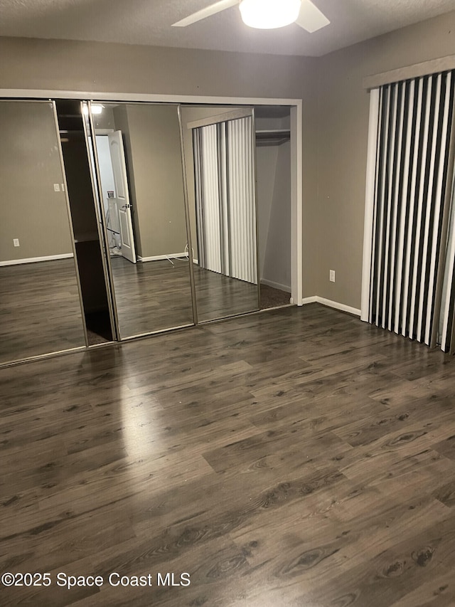 unfurnished bedroom with ceiling fan and dark wood-type flooring