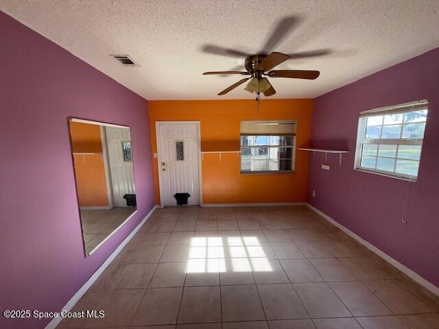 tiled spare room with a textured ceiling and ceiling fan