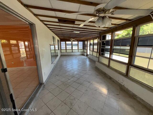 unfurnished sunroom featuring ceiling fan