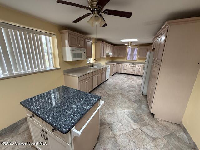 kitchen with white appliances, ceiling fan, a kitchen island, light brown cabinets, and sink