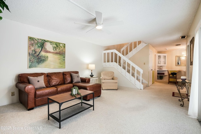 carpeted living room featuring ceiling fan and a textured ceiling