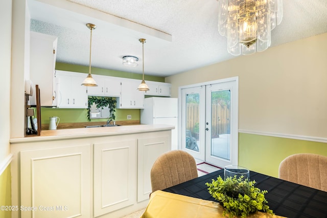 kitchen featuring pendant lighting, white cabinetry, sink, a textured ceiling, and french doors