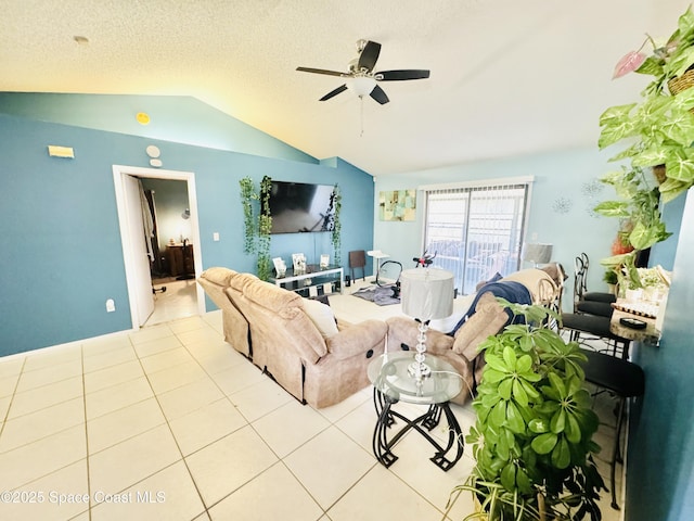 tiled living room featuring ceiling fan, vaulted ceiling, and a textured ceiling