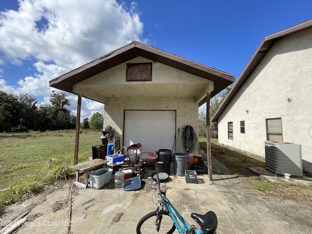 back of house featuring cooling unit, a garage, a lawn, and an outbuilding