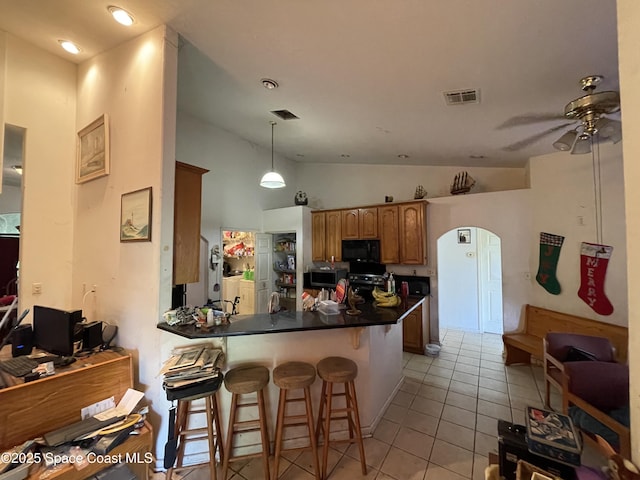 kitchen featuring vaulted ceiling, appliances with stainless steel finishes, a kitchen breakfast bar, hanging light fixtures, and kitchen peninsula