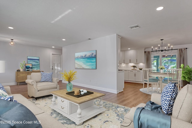 living room with a notable chandelier and light hardwood / wood-style flooring