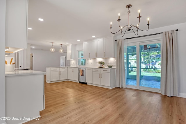 kitchen featuring dishwasher, white cabinetry, kitchen peninsula, light hardwood / wood-style flooring, and decorative light fixtures