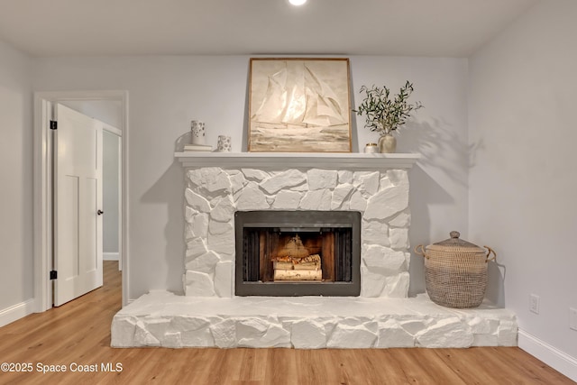 interior details featuring hardwood / wood-style floors and a stone fireplace