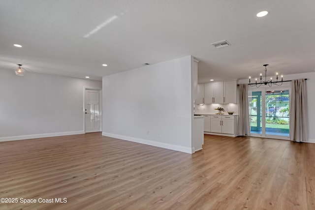 unfurnished living room with light hardwood / wood-style floors and a notable chandelier