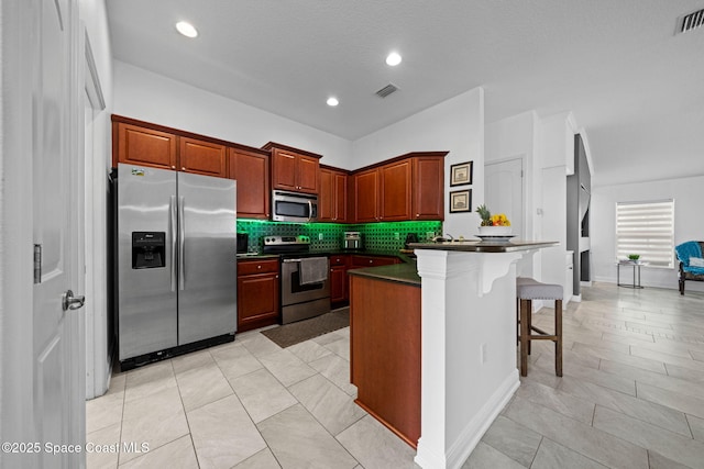 kitchen with backsplash, a kitchen bar, appliances with stainless steel finishes, and a center island