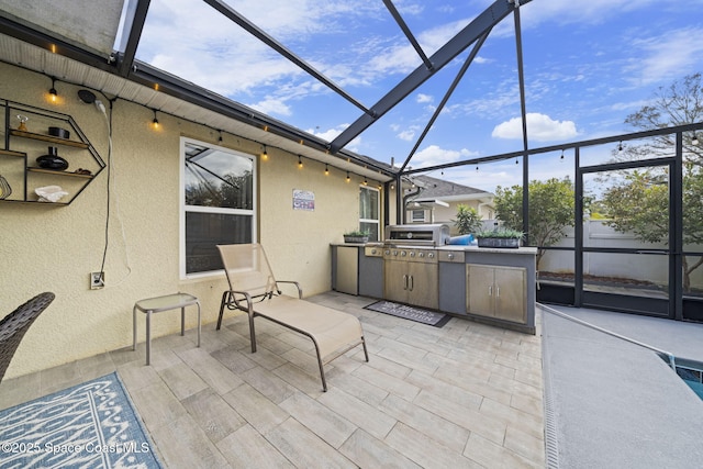 view of patio / terrace with glass enclosure, a grill, and an outdoor kitchen