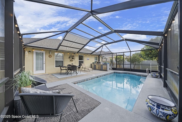 view of pool with a patio area, a lanai, and an outdoor kitchen