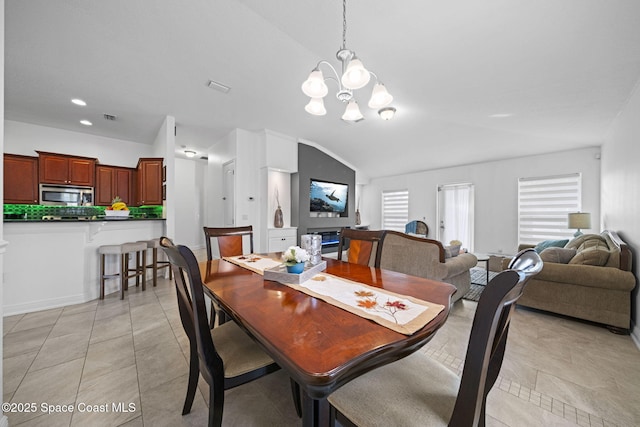 dining area with lofted ceiling, light tile patterned flooring, and a chandelier