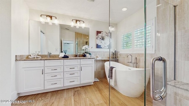 bathroom with tile walls, vanity, hardwood / wood-style floors, and plus walk in shower