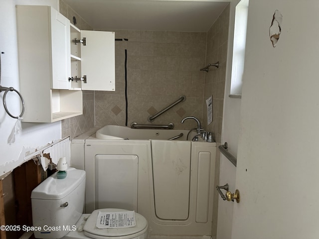 bathroom with toilet, a tub, washer / dryer, and decorative backsplash