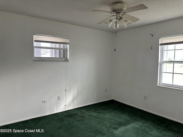 empty room with ceiling fan, a textured ceiling, and dark colored carpet