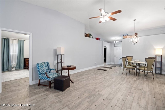 living area with high vaulted ceiling, ceiling fan with notable chandelier, and light wood-type flooring