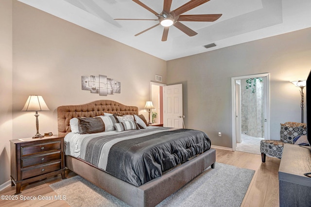 bedroom featuring ceiling fan, light hardwood / wood-style floors, and ensuite bath