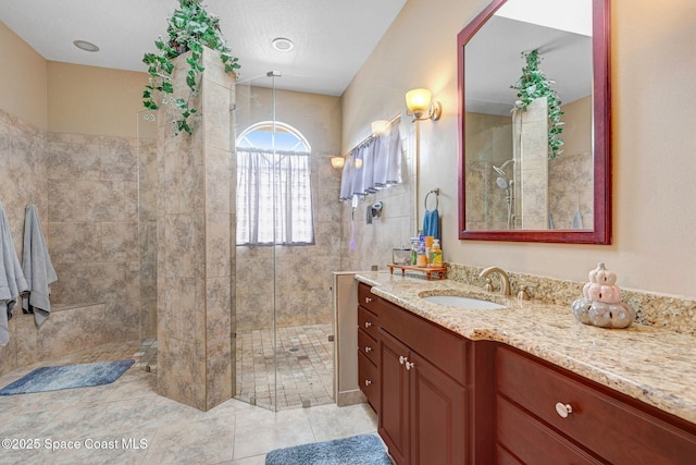 bathroom with vanity, tile patterned flooring, and a tile shower