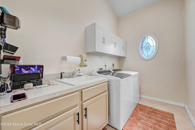 clothes washing area featuring light tile patterned floors, sink, separate washer and dryer, and cabinets