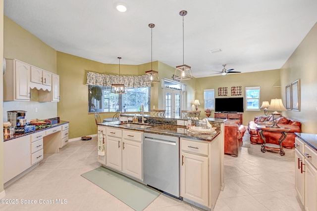 kitchen with ceiling fan with notable chandelier, pendant lighting, dark stone counters, sink, and stainless steel dishwasher