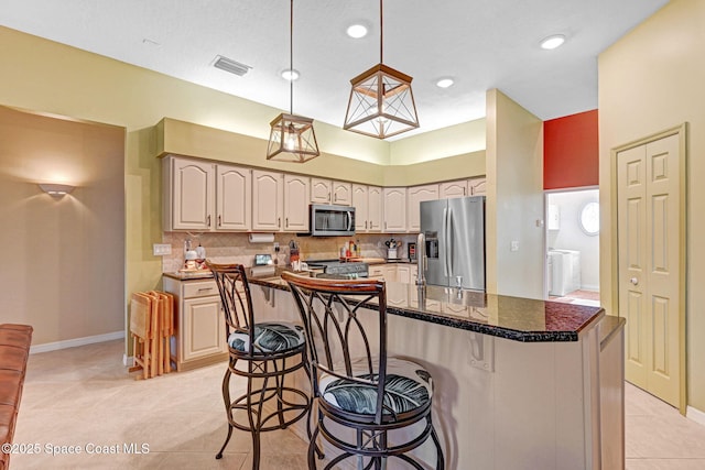 kitchen with light tile patterned floors, a kitchen bar, stainless steel appliances, decorative light fixtures, and a kitchen island