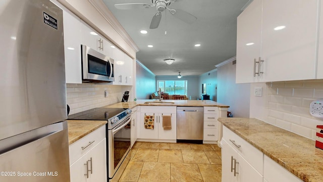 kitchen with white cabinetry, stainless steel appliances, tasteful backsplash, sink, and light stone counters