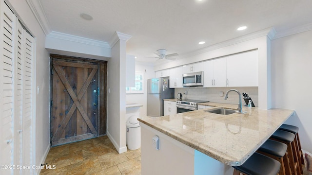 kitchen with white cabinetry, kitchen peninsula, stainless steel appliances, light stone counters, and sink