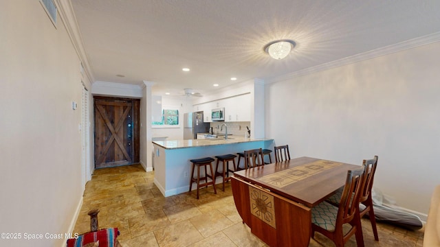 dining area featuring ceiling fan, sink, and ornamental molding