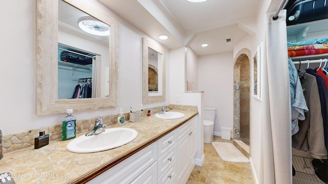 bathroom featuring toilet, a shower, and vanity